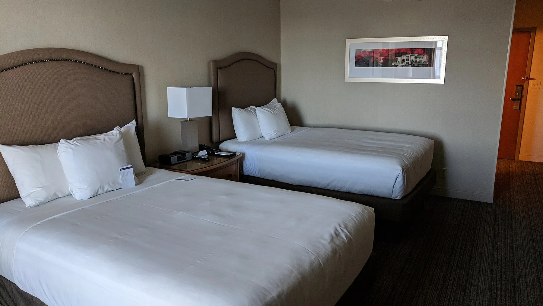 A standard hotel room with two made beds and a clear path to the door