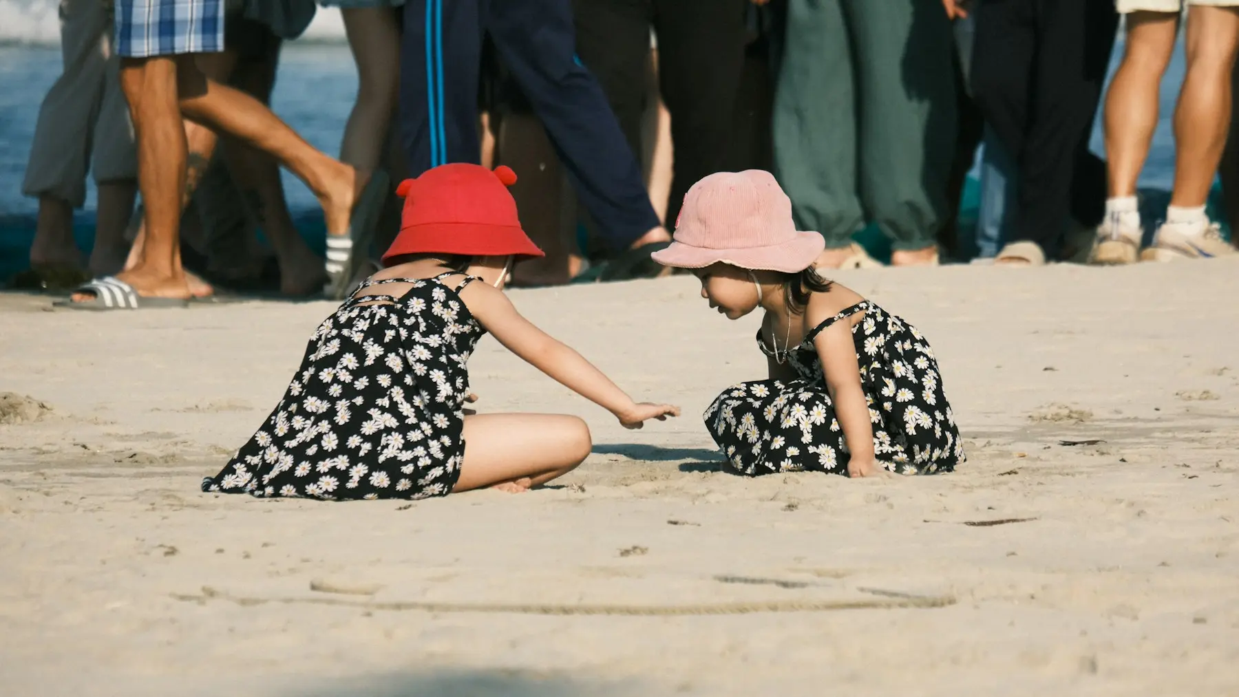 Two children wearing sun hats while playing on a beach